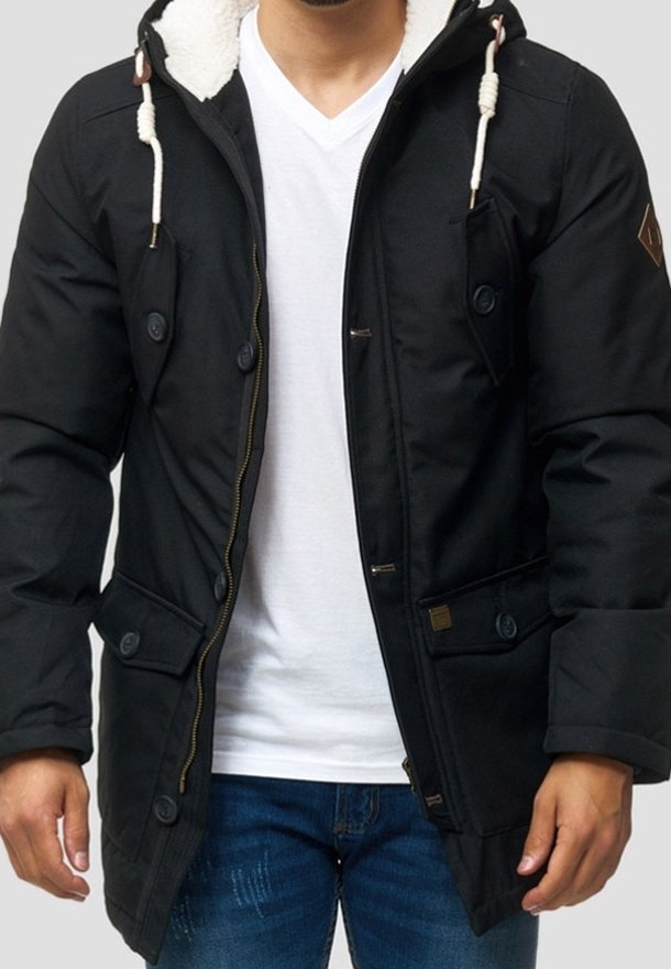 Veste matelassée noire avec une capuche doublée en fausse fourrure, fermeture éclair et boutons, plusieurs poches avant, et cordons de serrage contrastants.