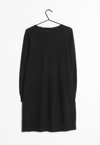 Abito nero lavorato a maglia con maniche lunghe e scollatura rotonda, appeso a un gancio di metallo nero su uno sfondo bianco.