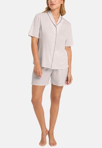 Grå kortärmad pyjamasuppsättning med kontrasterande mörka detaljer, bestående av skjorta med knappar och shorts med elastisk midja, mjukt material, avslappnad passform.