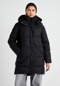 Abrigo puff negro con capucha, que presenta paneles acolchados horizontales, bolsillos con cremallera y botones a presión en el cuello para un cierre seguro.