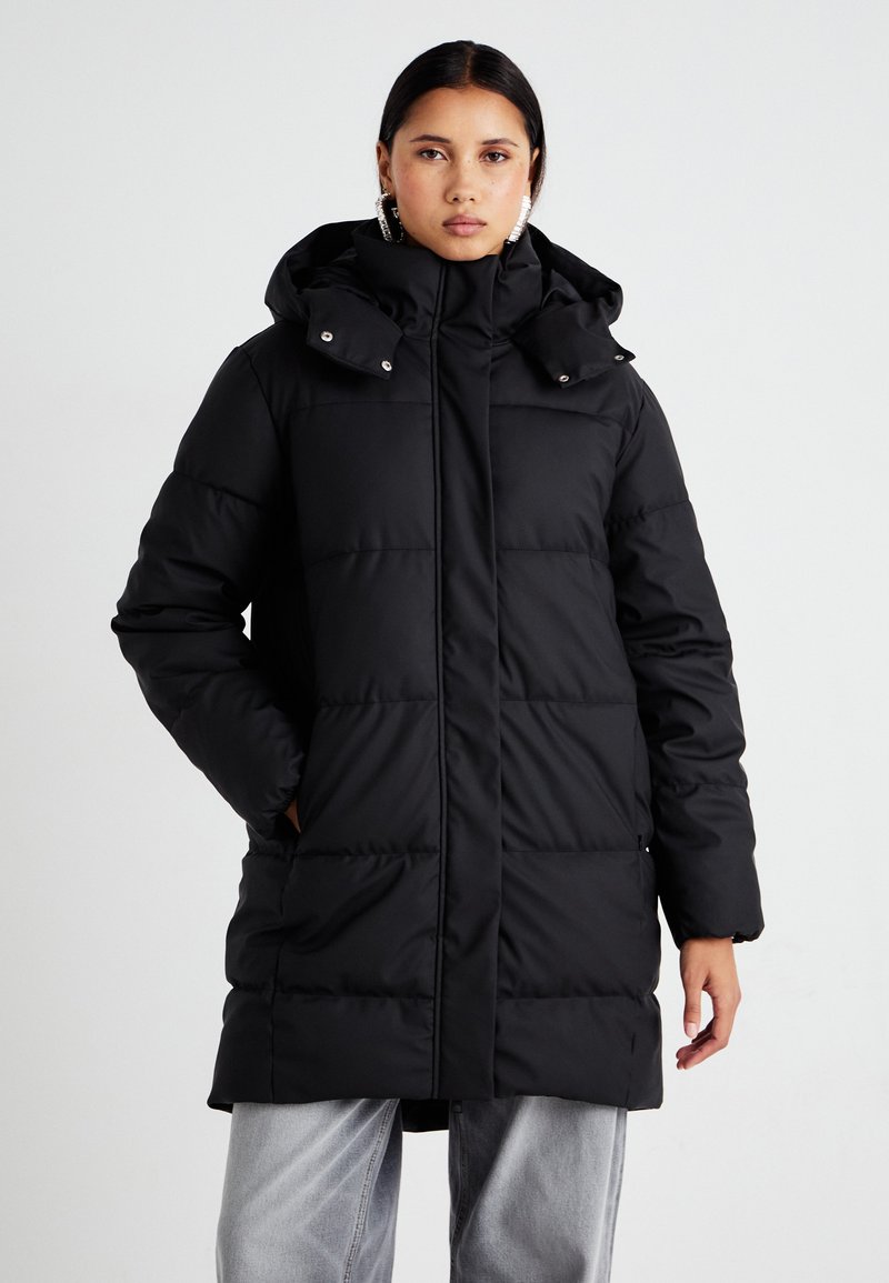 Abrigo puff negro con capucha, que presenta paneles acolchados horizontales, bolsillos con cremallera y botones a presión en el cuello para un cierre seguro.