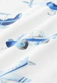 Puuvillakangas, jossa on valkoinen tausta ja vaaleansinisiä lentokoneita sekä potkurimalleja, esittelee erilaisia lentokonesuunnitelmia ja leikkisiä yksityiskohtia.