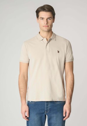 Polo beige realizzato in cotone, con colletto classico, maniche corte e un piccolo logo ricamato sul lato sinistro del petto.