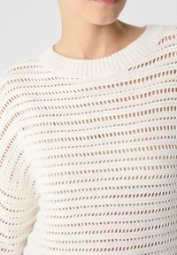 Weißer gestrickter Pullover mit lockerer Passform, der horizontale Lochmusterstreifen und einen gerippten Rundhalsausschnitt aufweist. Weiche Textur und lässiges Design.