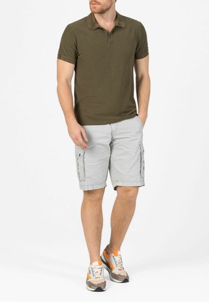 Olivgrünes gestreiftes Poloshirt mit drei Knöpfen. Helle graue Cargo-Shorts mit Taschen. Legere graue und orange Sneakers.