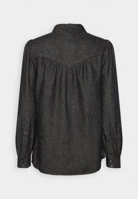 Chemise à manches longues gris foncé avec poignets boutonnés et détail d’empiècement, vue de dos sur un fond uni.