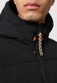 Sort isoleret jakke med lynlås, der har en farverig snoretræk ved kraven og glat, tekstureret stof.