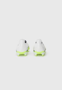 White soccer cleats featuring a textured surface with a subtle pattern, black accents, and bright green soles. View from the back.