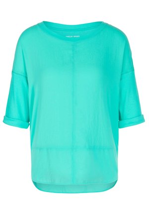 Chemise turquoise à manches courtes, coupe ample, avec poignets retroussés, encolure ronde et détails de coutures visibles à l'avant et à l'arrière.