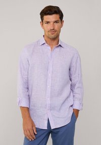 Camisa ligera de botones en lavanda con patrones de rayas verticales en azul y blanco. Cuenta con mangas enrollables y un corte ajustado.