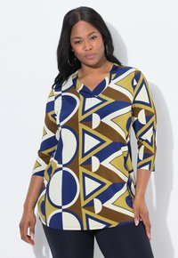 Bunt gemusterte Bluse aus dehnbarem Material mit geometrischen Mustern aus Kreisen und Dreiecken in Blau, Braun, Gelb und Creme. V-Ausschnitt-Design.