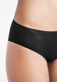 Svart modal tyg bikini med en mjuk textur och låg midja. Har en diskret logotypdetalj längs midjebandet.