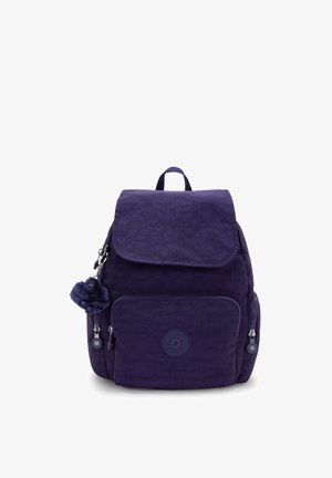 Dunkelvioletter Kipling-Rucksack mit Klappenverschluss, vorderer Reißverschluss-Tasche, Seitentaschen, Schlaufenhenkel und einem kleinen plüschigen Schlüsselanhänger.