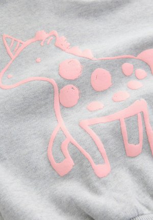 Gråt stof med et lyst lyserødt trykt design af en giraf med polkaprikker og stiliserede linjer, der viser en blød tekstur.