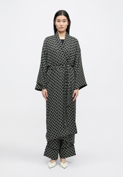 Μαύρο και άσπρο μοτίβο σε κιμονό στιλ ρόμπα με φαρδιά μανίκια, ζωνάκι στη μέση και ταιριαστά παντελόνια; το υλικό φαίνεται λείο με ελαφριά υφή.