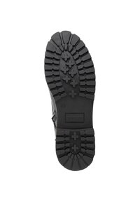 Zwarte rubberen schoenzool met een dik profiel en verhoogde kruis- en rechte lijnen, gelabeld met "TRAVELIN" en maat "42."