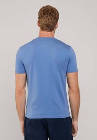 Camiseta de manga corta y cuello redondo en tejido azul claro, con una textura suave y forma ajustada, vista desde la parte posterior.