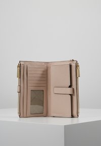 Light beige leather wallet organizer with multiple card slots, a transparent ID window, and gold-tone zipper hardware.