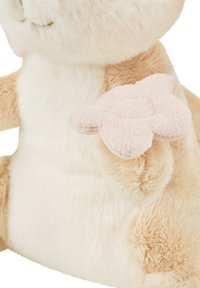 Plush toy with a soft beige body and white belly. Features a pink flower-shaped accent on one paw, made from textured fabric.