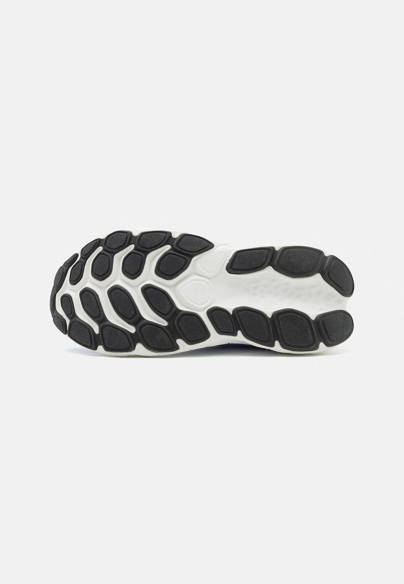 Suela de goma negra y blanca de un zapato con patrones de agarre texturizados, mostrada desde la parte inferior sobre un fondo blanco liso.