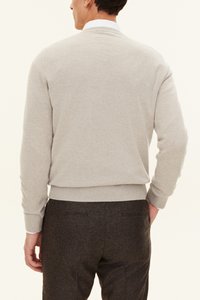 Pull gris avec un col rond, des poignets et une taille côtelés, affiché de dos. Porté avec un pantalon texturé sombre.