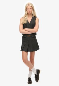 Top sin mangas a rayas negro y blanco con escote en V profundo y falda corta a juego. Completado con zapatos negros y calcetas blancas hasta la rodilla.