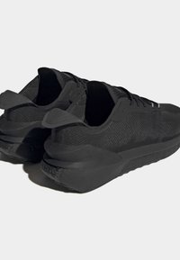 Černé sportovní boty s síťovaným svrškem a texturovanými detaily, vybavené polstrovanou podrážkou a pružnou patní smyčkou pro snadné nazouvání.