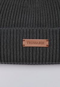 Szara prążkowana czapka z dzianiny z fakturowaną tkaniną oraz prostokątną brązową skórzaną metką z wytłoczonym napisem "TRUSSARDI."
