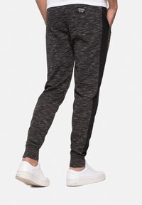 Svart och grå mönstrade joggers med en sidopanel i svart, elastiska mudd och fickor. Matchas med vita låga sneakers.
