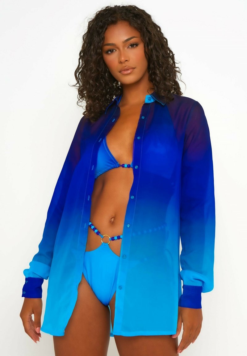 Chemise en voile avec dégradé bleu, à manches longues et fermetures à boutons, assortie d'un bikini bleu avec un accent en perles et un matériel circulaire.