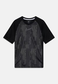Camiseta atlética negra con un patrón gris repetido de "NIKE" y un logotipo de Nike blanco en el centro. Las mangas raglán mejoran el movimiento.