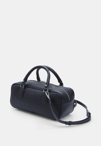 Sac de sport en cuir noir avec poignées arrondies, une bandoulière amovible, des détails de fermeture éclair argentés et une forme rectangulaire. Texture lisse.