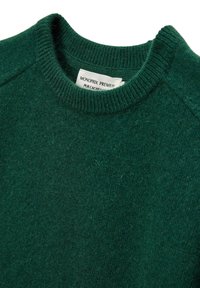 Pull en cachemire vert avec un col rond côtelé, texture douce et design minimal. L'étiquette indique "MONOPRIX PREMIUM PUR CACHEMIRE."