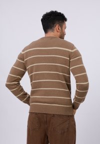 Bruine gestreepte trui van zacht breigaren, met horizontale crèmekleurige strepen, geribbelde boorden en een ronde hals.
