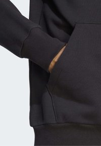 Svart sweatshirt med känguruficka, ribbade mudd och ett mjukt, texturerat tyg. Ärmarnas design ger en bekväm passform.