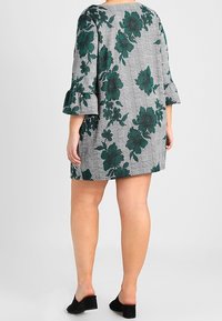 Sukienka w kwiatowy wzór w odcieniach zieleni i czerni na szarym kraciastym tle, z rękawami trzyczwartowymi ozdobionymi falbaną oraz prostym dołem.