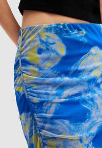 Σατέν φουστάνι σε μπλε και κίτρινο σχέδιο, με ρυτιδωτό σχέδιο, απαλή υφή και πλάγια σχισμή, φτιαγμένο από ελαστικό ύφασμα.