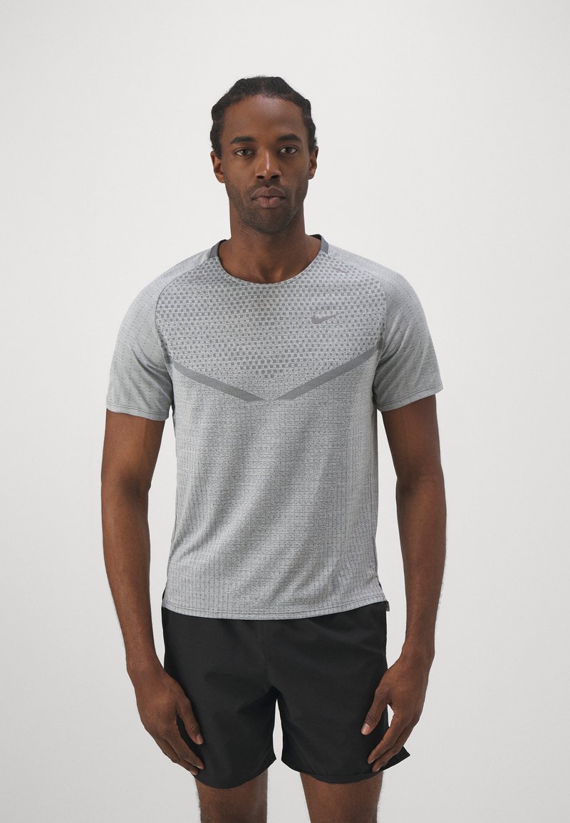 Hall hargne T-särk on kaunistatud tekstuuri mustriga, lühikeste varrukatega ja ümarate kaelustega. Koos mustade lühikestega. Rinnal on Nike logo.