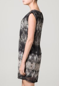 Vestido de manga corta en patrón negro y gris, con un corte holgado, escote redondo y textura de tela suave, llegando a la mitad del muslo.