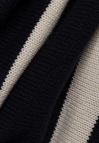 Sweter robiony na drutach z naprzemiennymi niebiesko-granatowymi i kremowymi poziomymi paskami. Tekstura jest miękka, z prążkowym wykończeniem na brzegach.