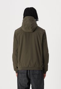 Olivenfarget hettegenser med en glatt tekstur, elastiske mansjetter og midje. Har flate sømmer og et minimalistisk design.