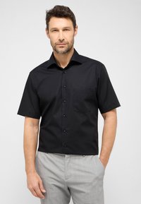 Zwarte short-sleeve shirt van gladde stof, met een knoopsluiting aan de voorkant, een spitse kraag en een enkele borstzak.