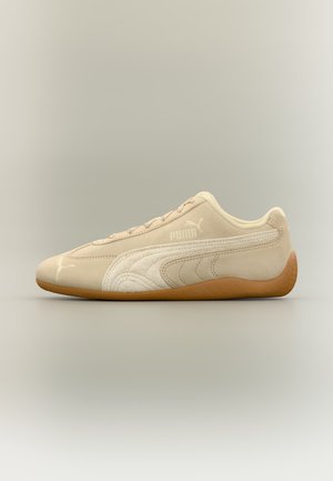 Baskets en daim beige Puma avec détail de bande blanche et semelle en gomme, vues de côté sur fond neutre.