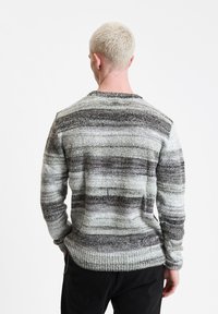 Strickpullover in Grautönen und Schwarz, mit horizontalen Streifen. Die gerippten Bündchen und der Saum runden das Design ab.