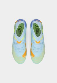 Ζευγάρι αθλητικών παπουτσιών ανοιχτού μπλε χρώματος με πορτοκαλί και κίτρινες λεπτομέρειες, πράσινες εσωτερικές σόλες με λογότυπα Puma και κωδικούς QR, σε θέα από πάνω.