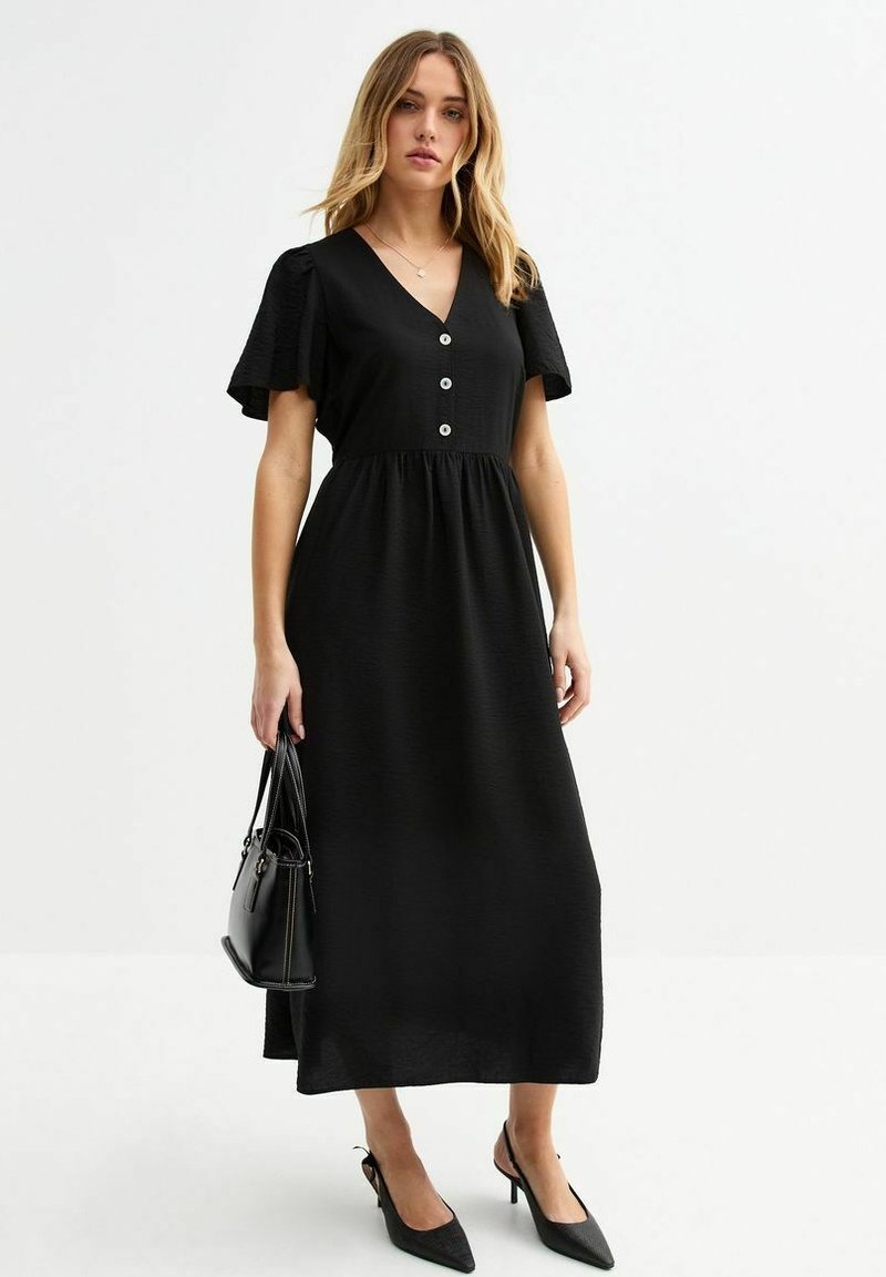 Vestido maxi negro con mangas cortas acampanadas, escote en V y detalle de tres botones en la parte delantera. Tejido suave y corte relajado.