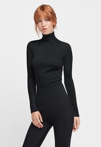 Schwarzes, geripptes Rollkragenoberteil aus elastischem Stoff. Eng anliegendes Design mit langen Ärmeln, glatter Textur und hohem Kragen.