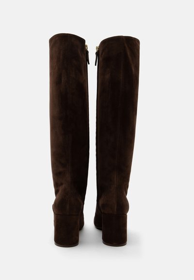 Bottes hautes en daim brun foncé avec talons carrés et fermetures éclair à l'arrière, vues de dos sur un fond neutre.