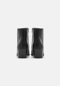 Stivali ankle in pelle nera con una finitura liscia, punta rotonda e tacco grosso. Dotati di una zip laterale per una facile indossabilità.