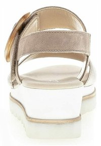 Beige suede sandals with a rear strap, white chunky heel, and round gold-tone embellishment. Smooth texture and open-back design.